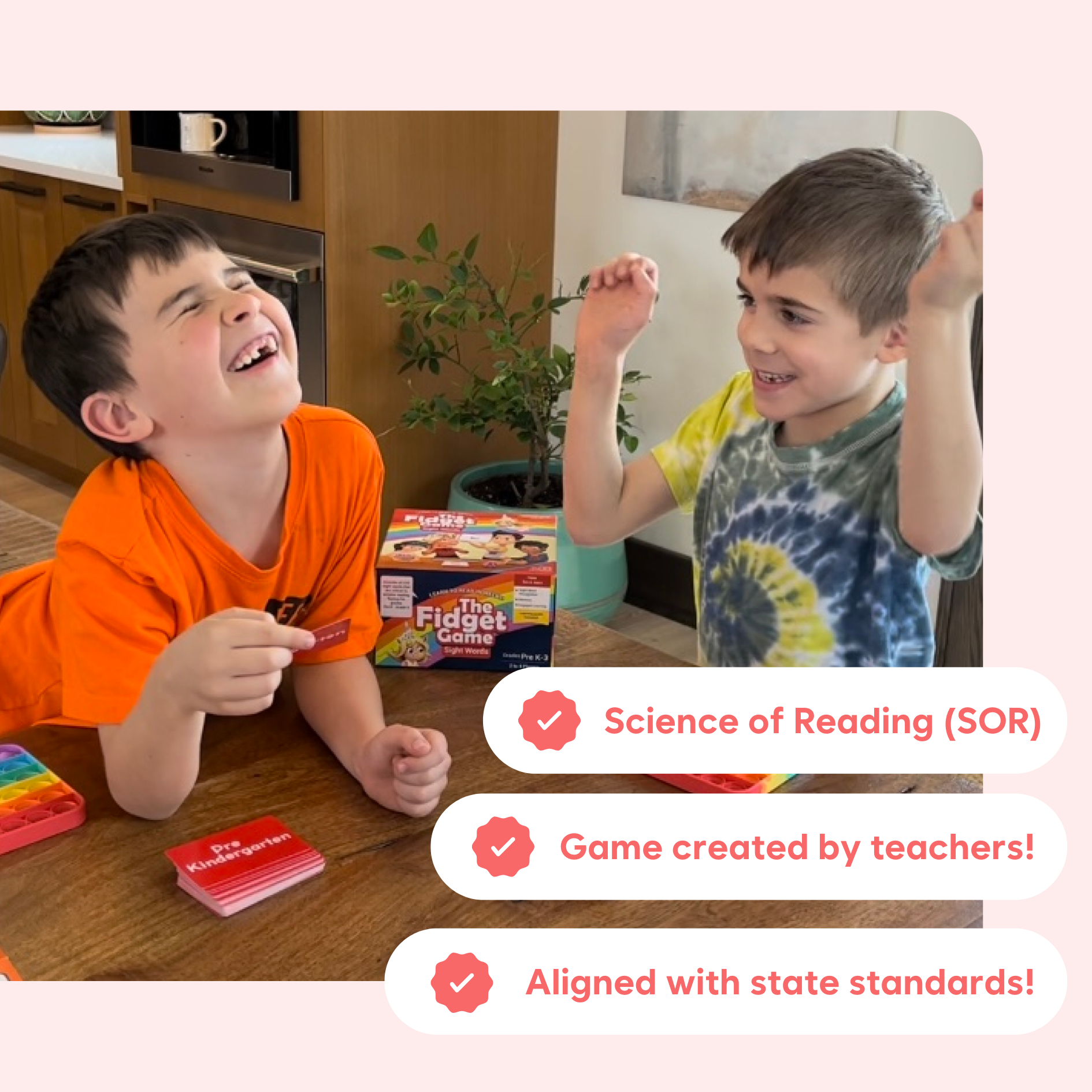 Two boys happily playing The Fidget Game: Sight Words Edition | Learning Card Game for Kids with ADHD & Sensory Needs at a table with game cards and a pop-it toy nearby.