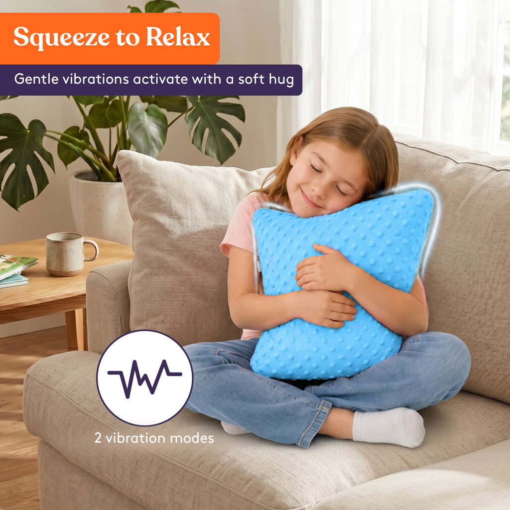 Child sitting cross-legged on a couch hugging a blue Sensory Vibrating Pillow – Pressure-Activated Calming Support for Kids & Adults, 12” Plush with Textured Bumps, 3 Vibration Modes, Music & Voice Recording (Blue) with a relaxed smile.