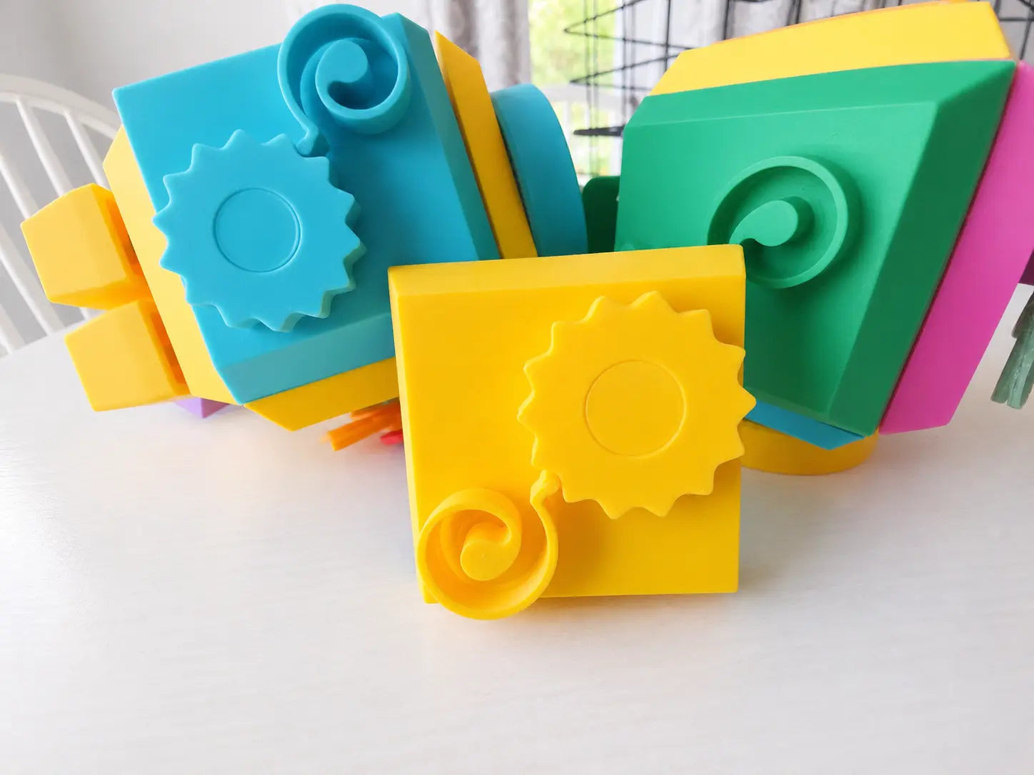 Close-up of colorful plastic pieces of the Modular Fidget Cube | Swappable Sensory Toy for Kids 4+ | 4 Inch, designed with gears and textured shapes for sensory engagement.