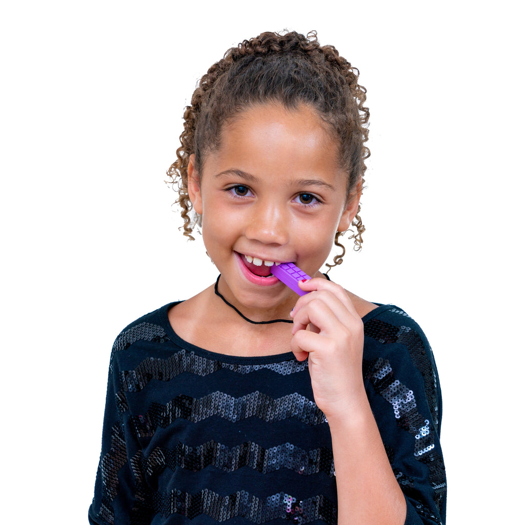 Young girl wearing a Chewy Blocks Necklace - Calming Textured Chewy Silicone Pendant for Autism & Oral Motor Special Needs Kids, gently biting the purple pendant for sensory relief.