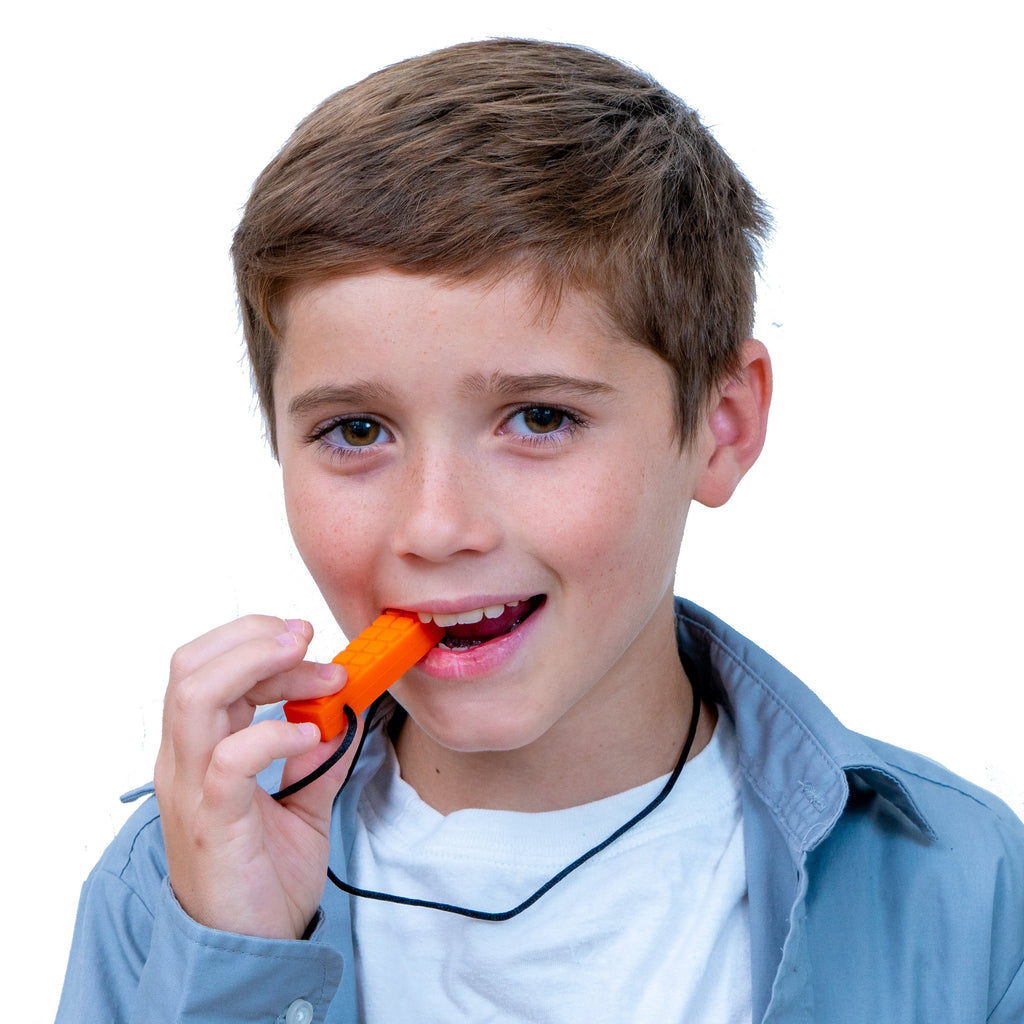 Young boy wearing a blue shirt and white t-shirt using the Chewy Blocks Necklace - Calming Textured Chewy Silicone Pendant for Autism & Oral Motor Special Needs Kids to help with oral sensory needs.